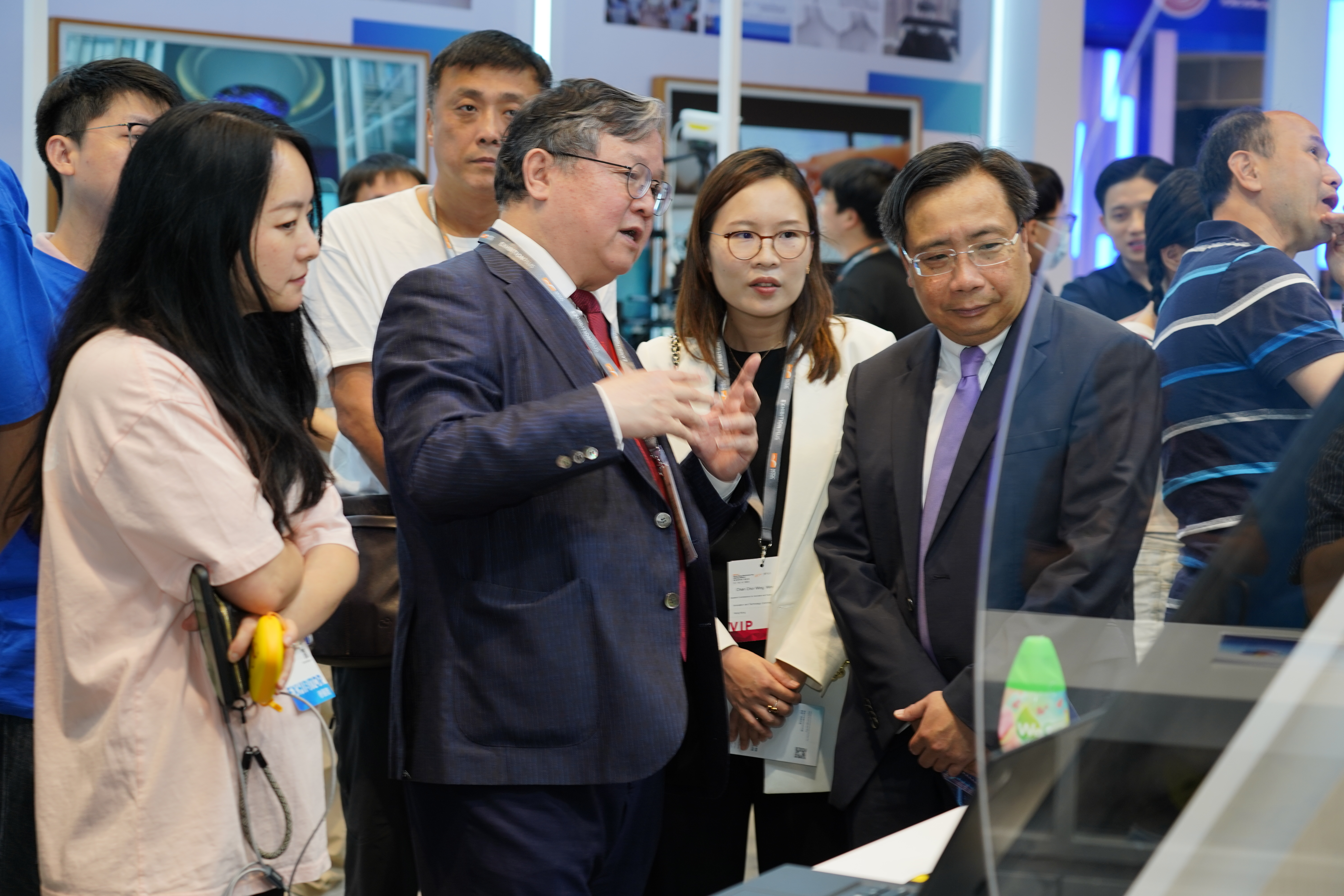 Prof. Guo (front row second left) introduces various research projects and achievements of HKGAI to Mr. Ivan LEE Kwok-Bun (front row first right), Commissioner for Innovation & Technology, and Ms. Winnie CHAN Chor-Wing (front row second right), Assistant Commissioner for Innovation and Technology (Research Clusters) of the Hong Kong Special Administrative Region Government, who visit the booth.