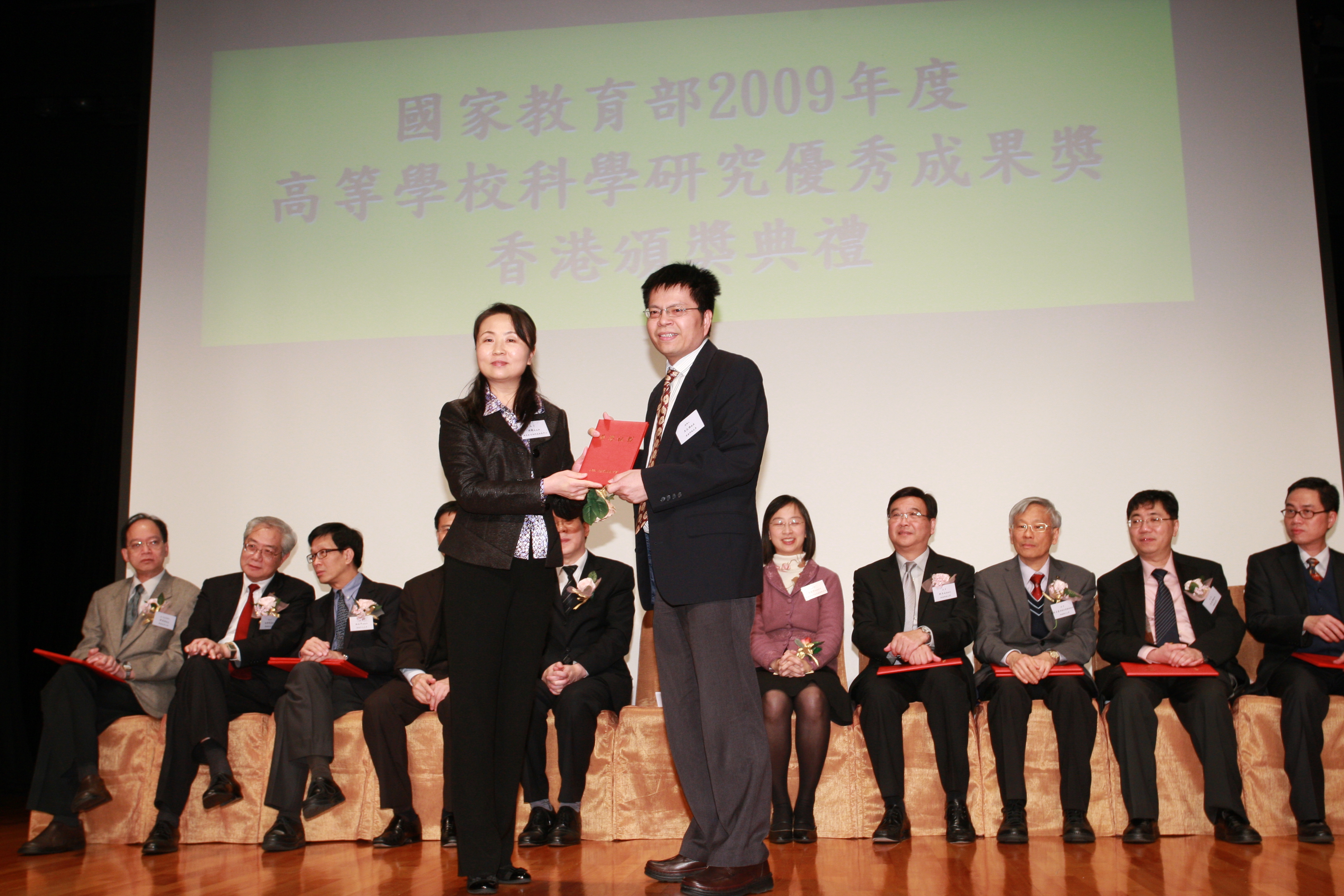 王 文 雄 教 授 （ 右 ） 接 受 國 家 教 育 部 科 技 發 展 中 心 副 主 任 周 靜 女 士 頒 發 獎 勵 証 書	