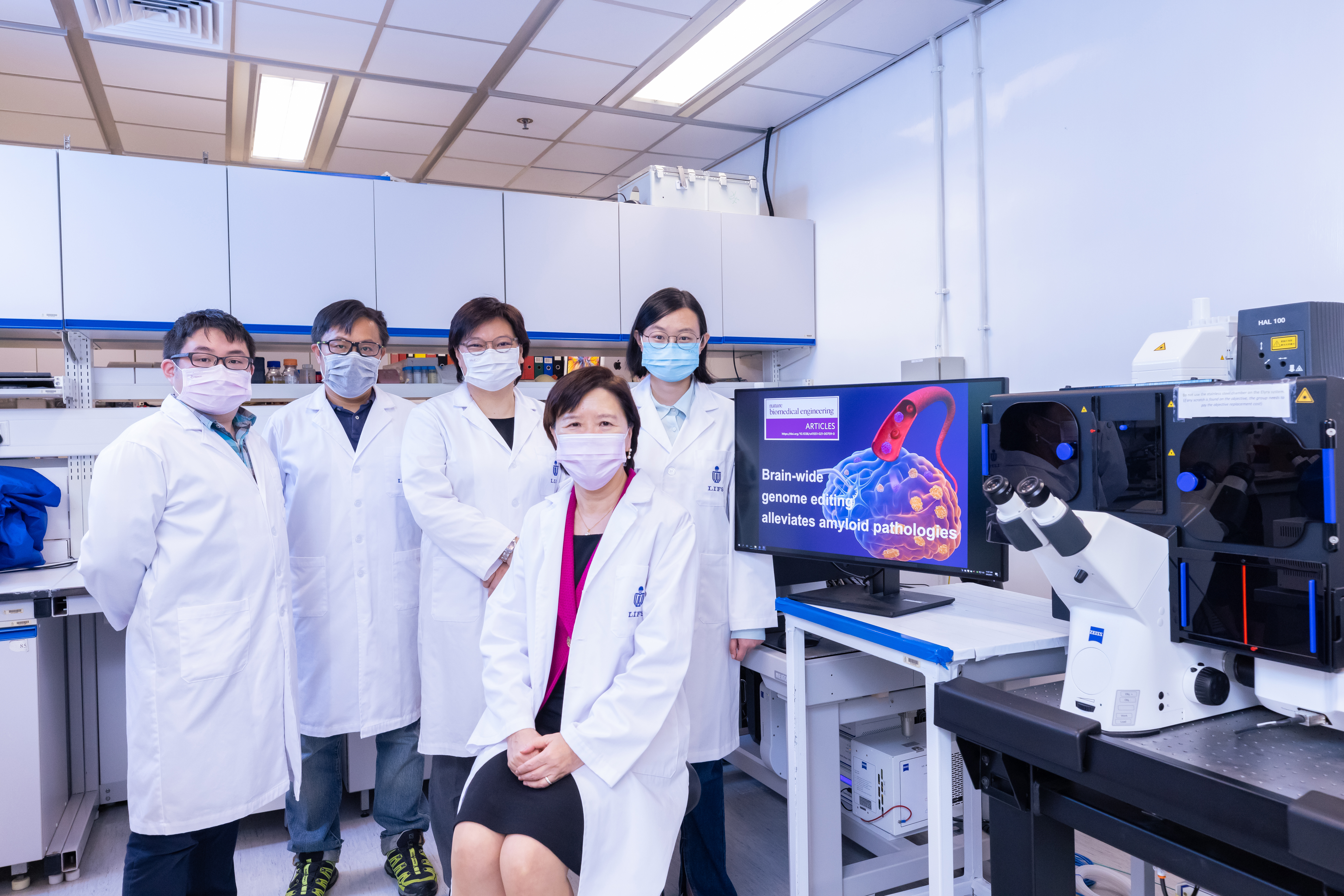 HKUST’s Vice-President for Research and Development, Prof. Nancy Ip (second right) and her research team members – including doctoral student and co-first author of this research paper, Ms. Stephanie DUAN Yangyang (first right) – used the confocal imaging system (pictured) to demonstrate how disruption of a familial Alzheimer’s disease mutation by genome editing strategy reduces disease pathology. 