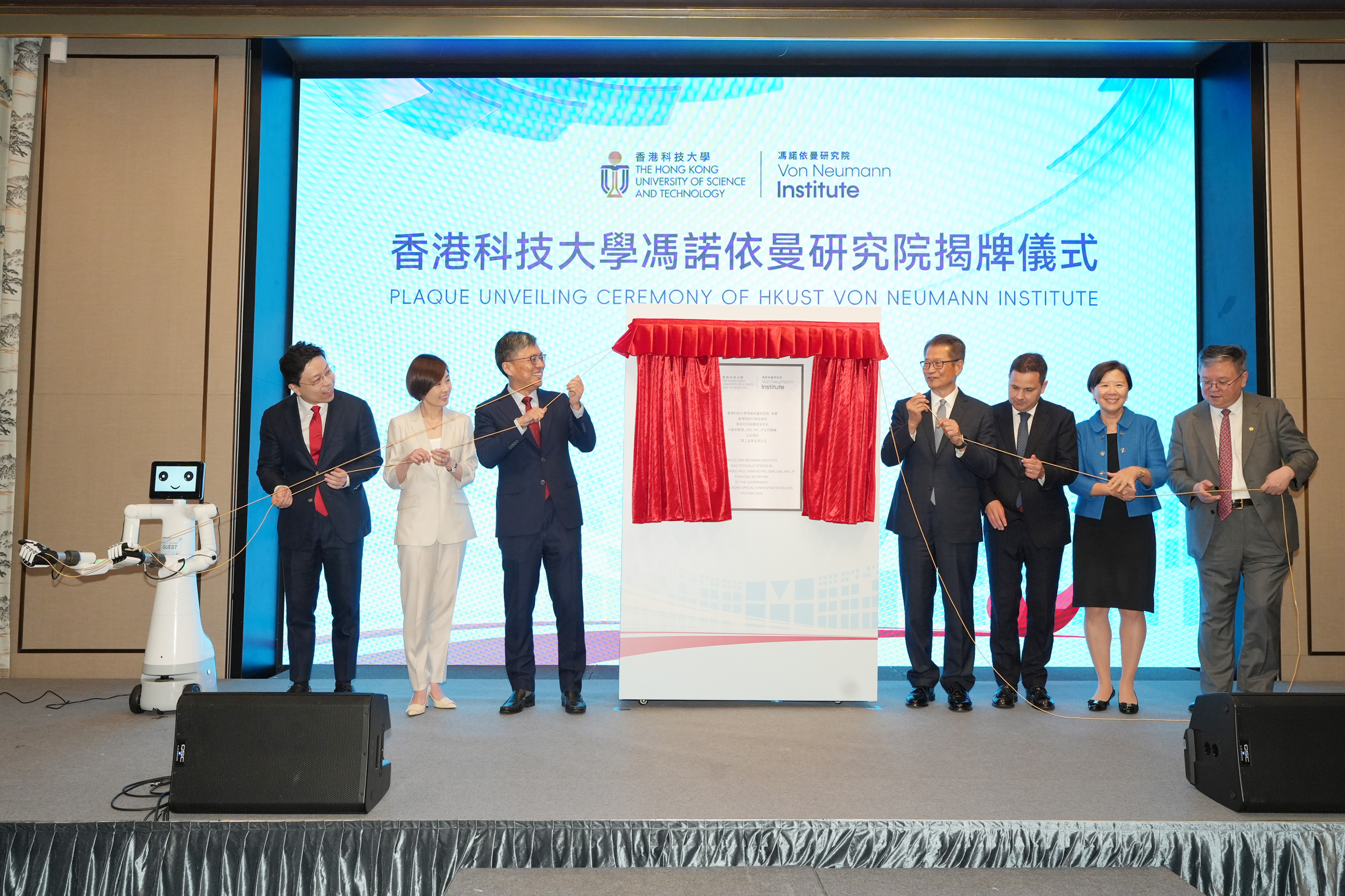 香港特別行政區財政司司長陳茂波（右四）、匈牙利駐香港總領事柯泰安（右三） 、香港投資管理有限公司（港投公司）行政總裁陳家齊（左二），科大校董會主席沈向洋教授（左三）、校長葉玉如教授（右二）以及首席副校長郭毅可教授（右一）等，會同科大馮諾依曼研究院（Von Neumann Institute）院長賈佳亞教授（左一）及其團隊研發的AI機械人Vonnex，主持研究院的揭幕儀式。