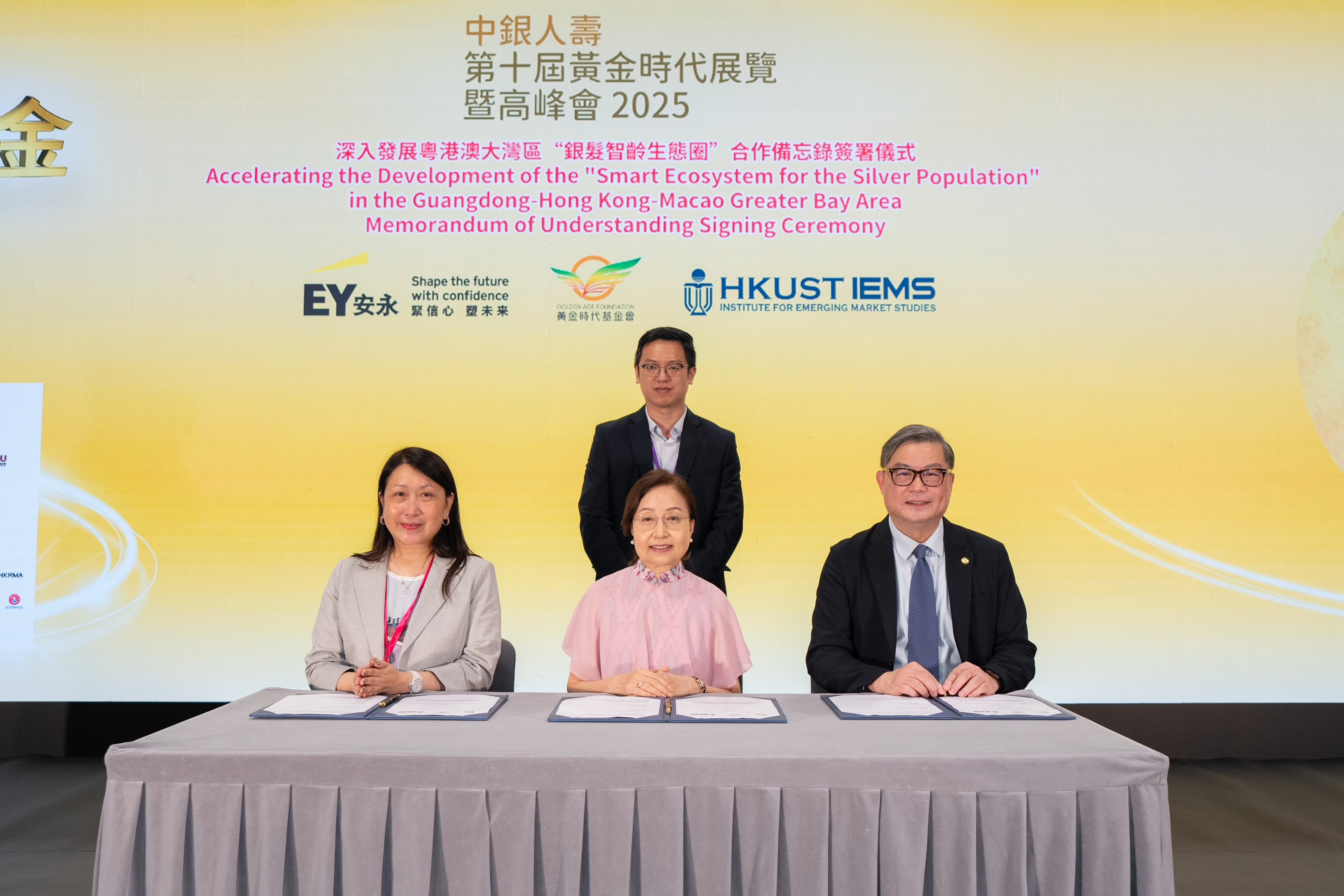  三方代表香港科技大学副校长（行政）及新兴市场研究所署理所长谭嘉因教授（前排右）、安永香港及澳门区主管合伙人李舜儿（前排左）及黄金时代基金会创办人及主席容蔡美碧教授（前排中）及签署见证人劳工及福利局副局长何启明太平绅士（后排）合影。 