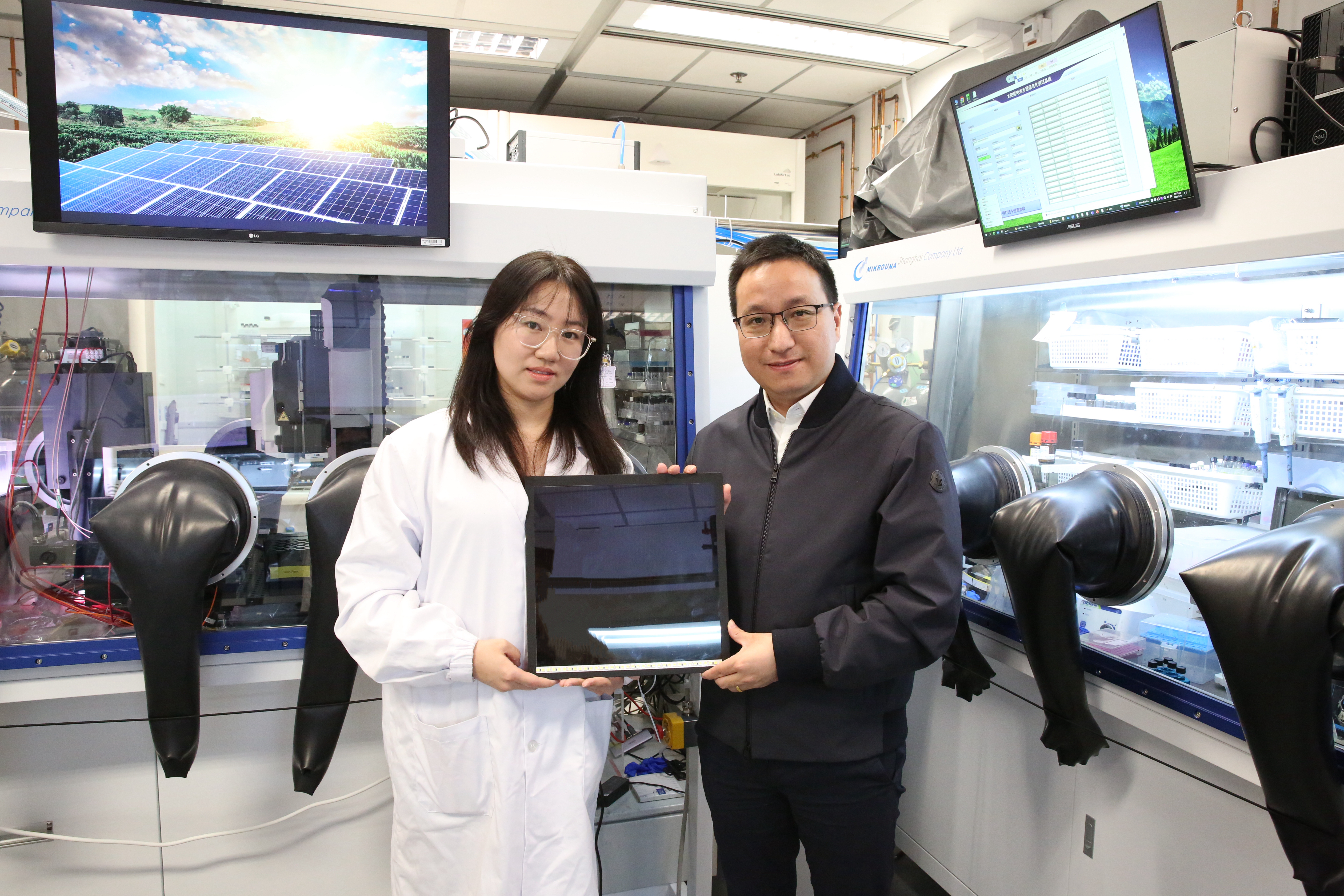 Prof. ZHOU Yuanyuan (right), corresponding author of the study, and Dr. HAO Mingwei (left), co-first author of the study, hold a perovskite solar panel made with the “slow-release solvent” strategy.
